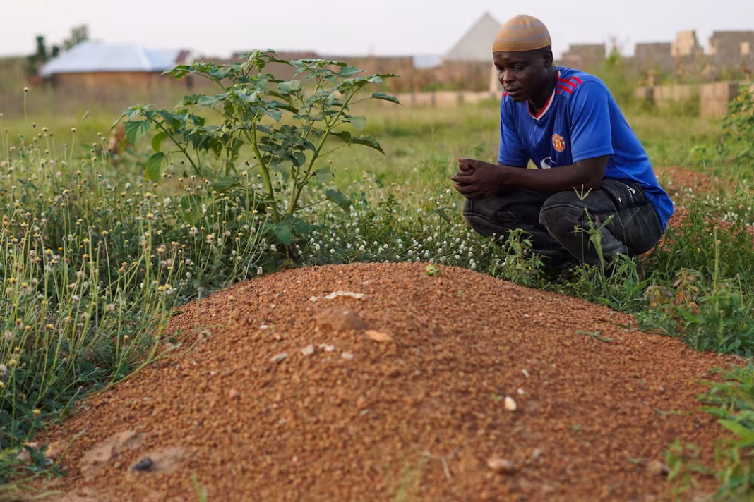 A man praying at a grave in Nigeria after the death of his son, one of 37 artisanal miners who died in custody.